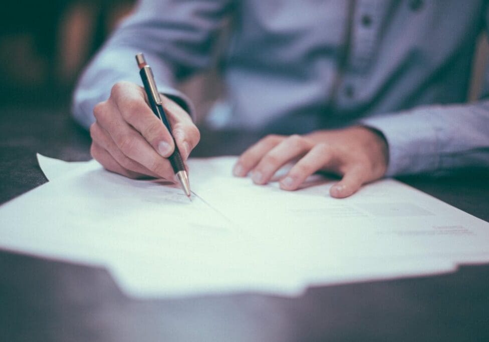 Person signing a document with a pen.